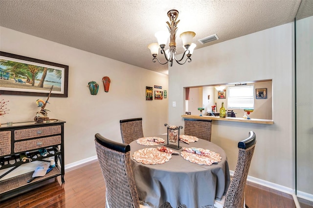 dining room featuring dark hardwood / wood-style flooring, a chandelier, and a textured ceiling