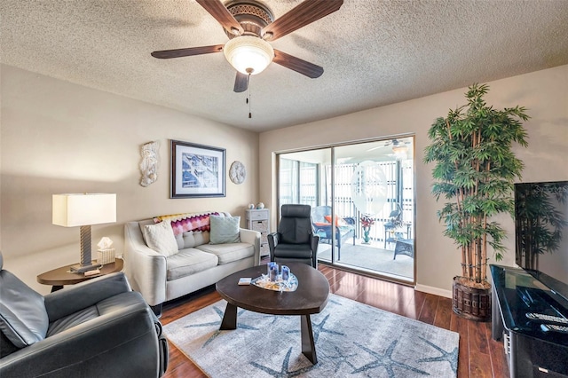 living room featuring ceiling fan, dark wood-type flooring, and a textured ceiling