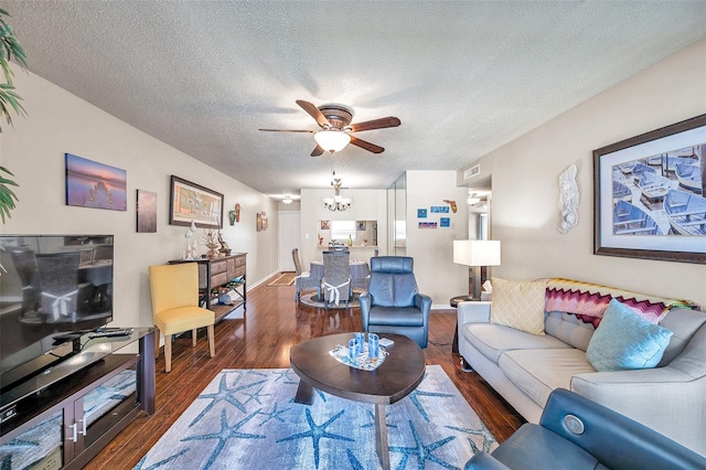 living room with dark wood-type flooring, ceiling fan with notable chandelier, and a textured ceiling