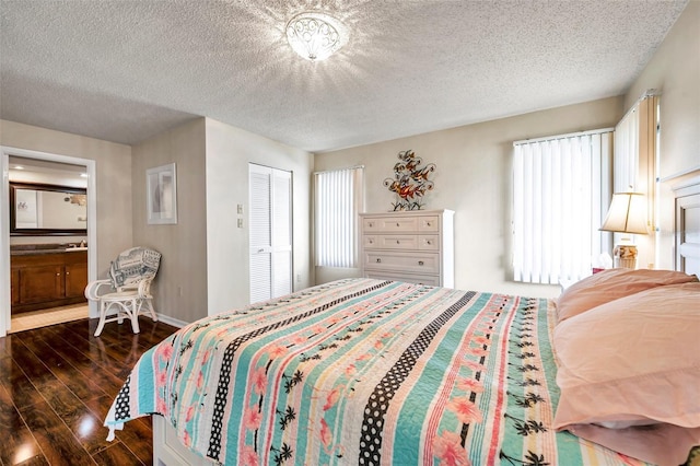 bedroom featuring a textured ceiling, a closet, dark hardwood / wood-style flooring, and ensuite bath