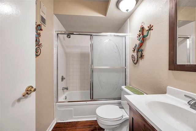 full bathroom featuring toilet, hardwood / wood-style floors, vanity, and shower / bath combination with glass door