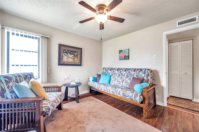 living room with ceiling fan, a textured ceiling, and dark hardwood / wood-style floors