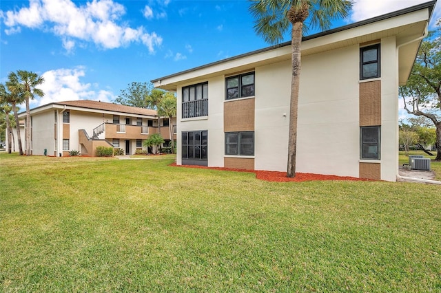 rear view of property featuring central AC unit and a lawn