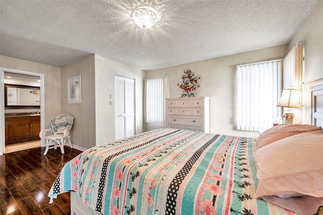 2700 Nebraska Ave Unit 3-201, Palm Harbor, FL 34684 - bedroom featuring dark wood-style floors, a textured ceiling, baseboards, a closet, and connected bathroom