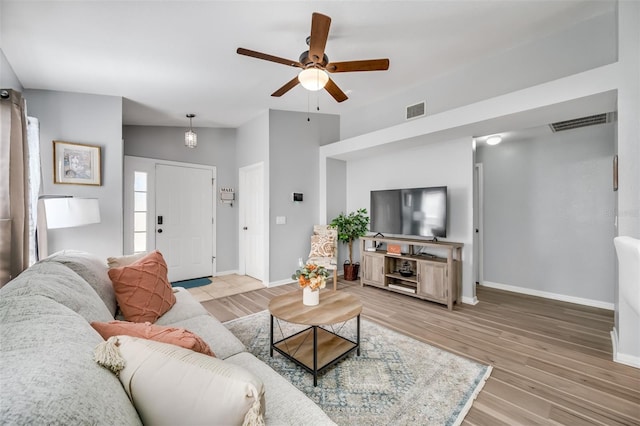 living room featuring ceiling fan, vaulted ceiling, and light wood-type flooring