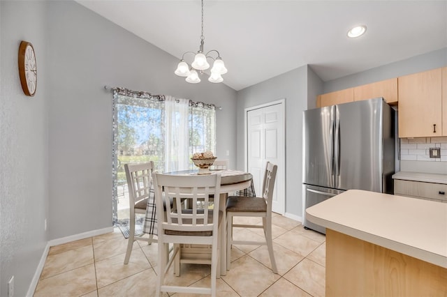 tiled dining room featuring lofted ceiling and a notable chandelier