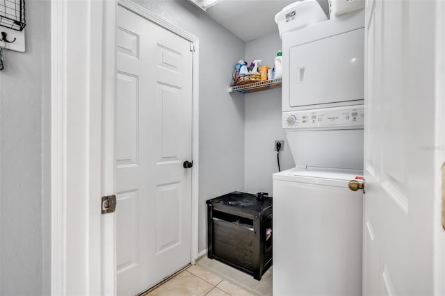 laundry room featuring light tile patterned floors and stacked washer / dryer