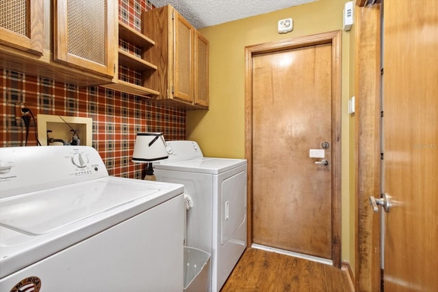 laundry room featuring hardwood / wood-style floors, washer and dryer, a textured ceiling, and cabinets