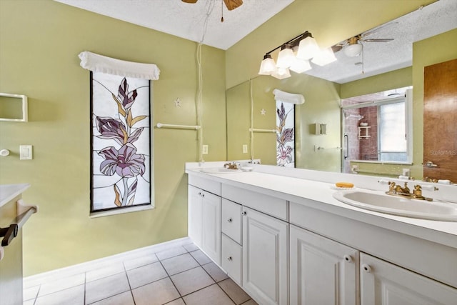 bathroom with ceiling fan, vanity, tile patterned flooring, a shower with shower door, and a textured ceiling