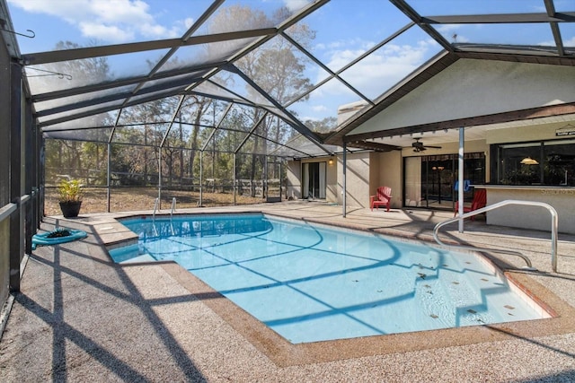 view of pool with glass enclosure, a patio area, exterior bar, and ceiling fan