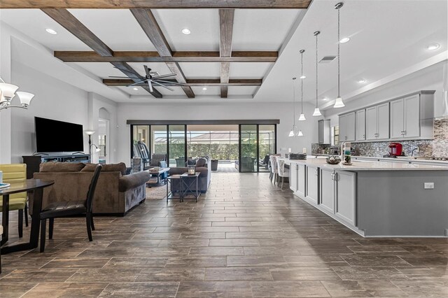 interior space featuring decorative light fixtures, backsplash, beam ceiling, coffered ceiling, and ceiling fan with notable chandelier