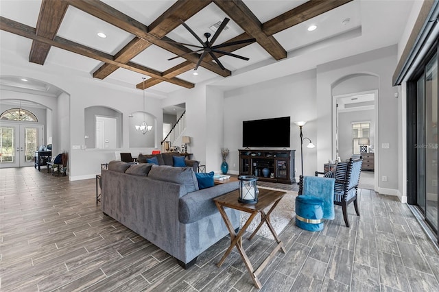 living room featuring ceiling fan with notable chandelier, beam ceiling, french doors, and coffered ceiling