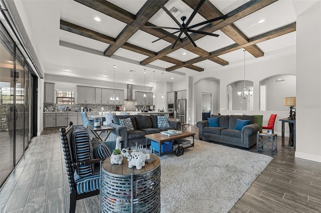 living room featuring beam ceiling, coffered ceiling, and a notable chandelier