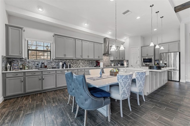 kitchen with stainless steel appliances, pendant lighting, a breakfast bar, and an island with sink