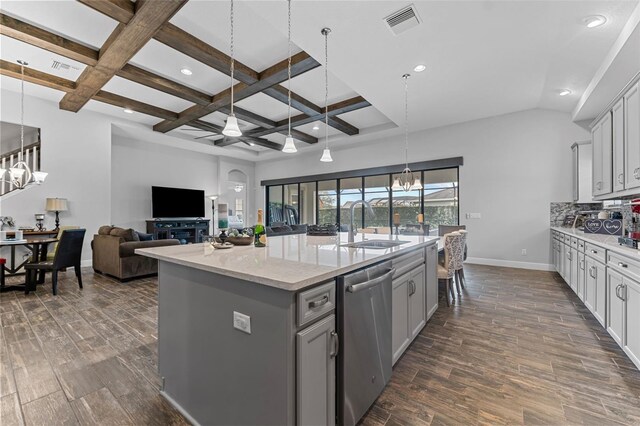 kitchen with an island with sink, gray cabinetry, stainless steel dishwasher, ceiling fan with notable chandelier, and light stone counters