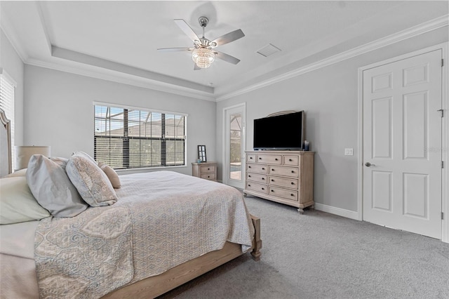 carpeted bedroom featuring ceiling fan, crown molding, a tray ceiling, and multiple windows