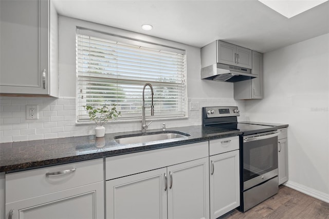 kitchen featuring gray cabinets, wood-type flooring, sink, stainless steel electric stove, and dark stone counters