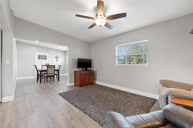 living room featuring ceiling fan, light wood-type flooring, and vaulted ceiling