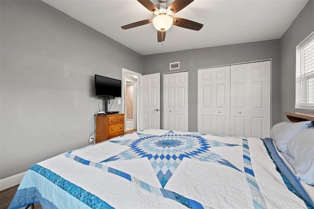 bedroom with ceiling fan, two closets, and wood-type flooring