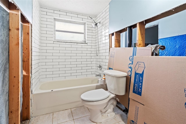 bathroom featuring toilet, tiled shower / bath combo, and tile patterned flooring