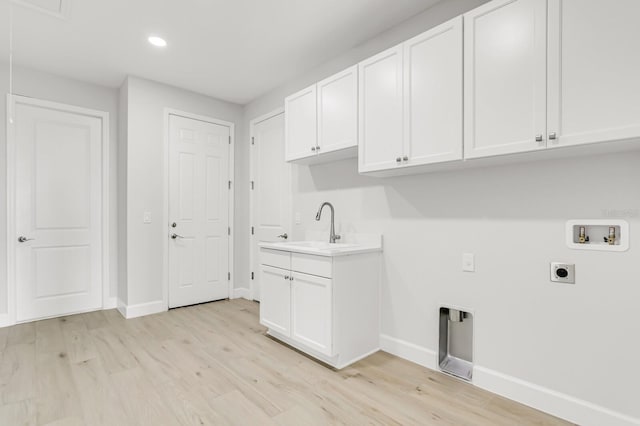 washroom featuring sink, cabinets, hookup for a washing machine, hookup for an electric dryer, and light hardwood / wood-style floors