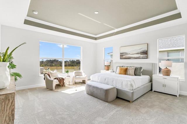 bedroom with light colored carpet, ornamental molding, and a tray ceiling