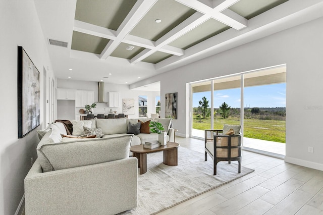 living room featuring beamed ceiling, coffered ceiling, a towering ceiling, and light hardwood / wood-style flooring