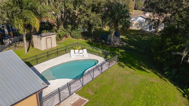 view of swimming pool featuring a yard and a storage unit