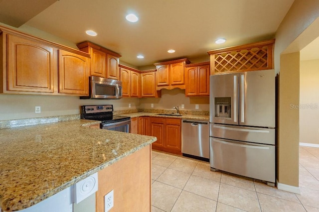 kitchen with kitchen peninsula, sink, light tile patterned flooring, appliances with stainless steel finishes, and light stone counters