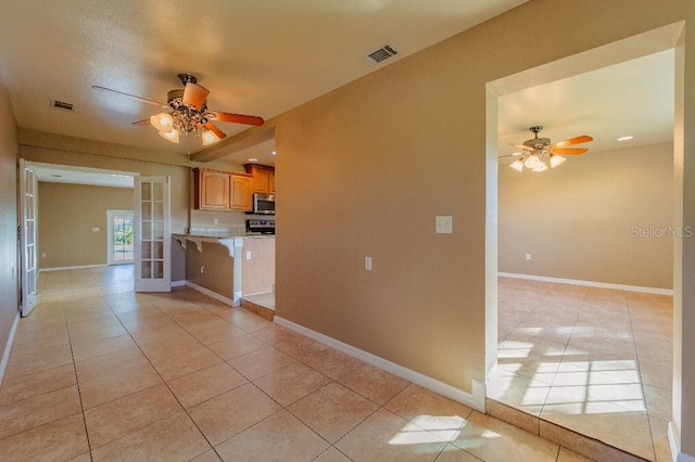 kitchen with a textured ceiling, appliances with stainless steel finishes, french doors, ceiling fan, and light tile patterned floors