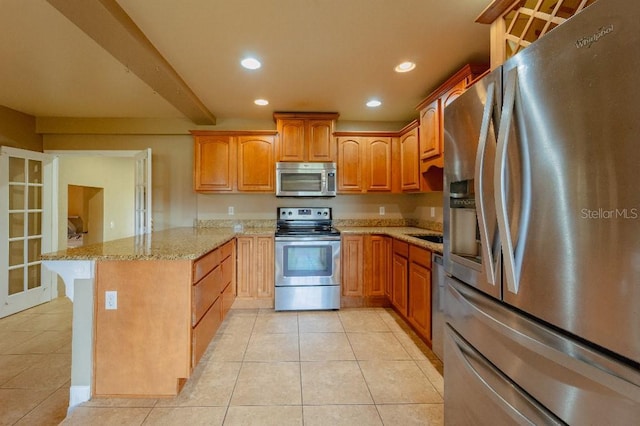 kitchen with light tile patterned floors, kitchen peninsula, appliances with stainless steel finishes, and light stone counters