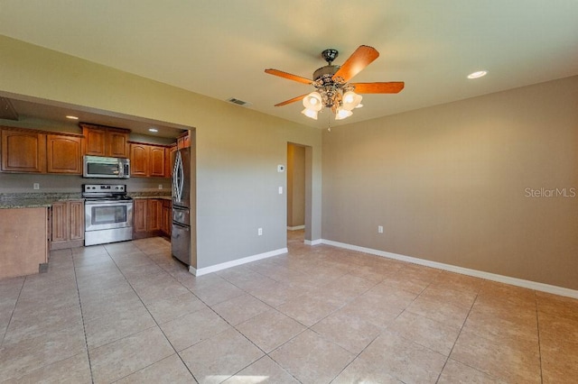 kitchen featuring ceiling fan, light tile patterned floors, appliances with stainless steel finishes, and stone counters