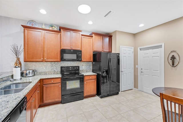 kitchen with tasteful backsplash, black appliances, sink, light stone countertops, and light tile patterned floors