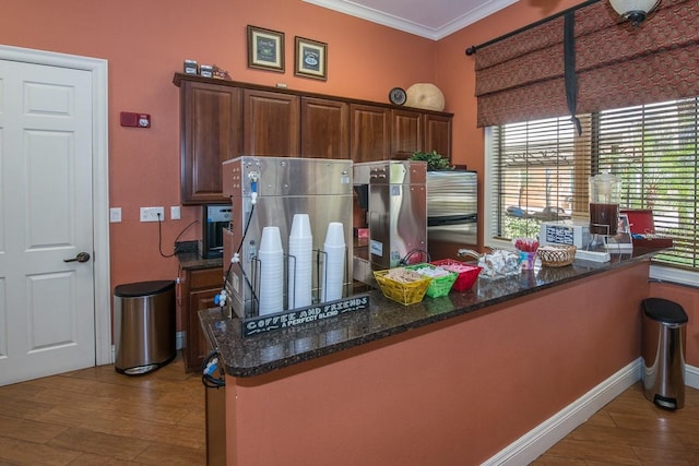 kitchen featuring kitchen peninsula, dark stone countertops, crown molding, and light hardwood / wood-style floors