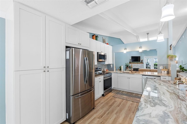 kitchen with pendant lighting, white cabinets, stainless steel appliances, tasteful backsplash, and light hardwood / wood-style flooring