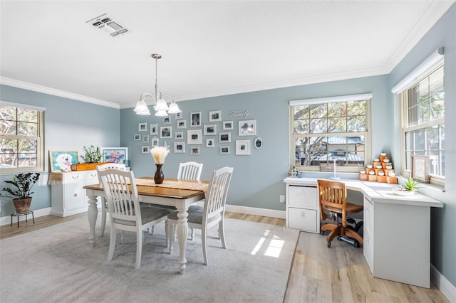 dining room with a chandelier, light wood-type flooring, and ornamental molding