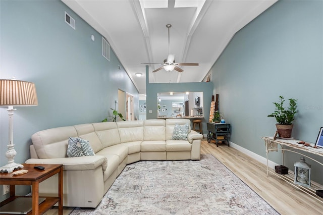 living room with ceiling fan, light wood-type flooring, and vaulted ceiling