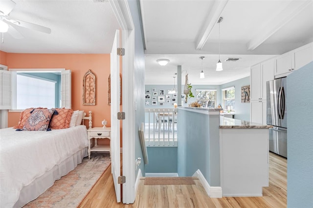 bedroom featuring ceiling fan, stainless steel fridge, light hardwood / wood-style flooring, and beamed ceiling