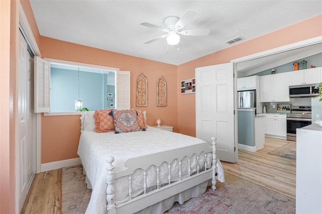 bedroom with ceiling fan, vaulted ceiling, light wood-type flooring, and stainless steel refrigerator