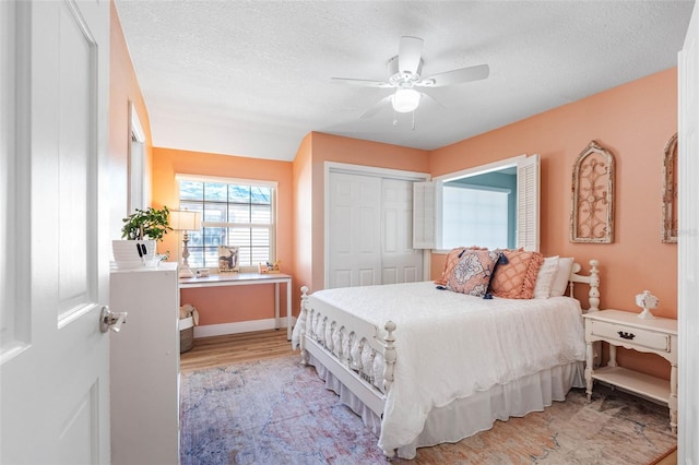 bedroom featuring ceiling fan, light hardwood / wood-style floors, a textured ceiling, and a closet