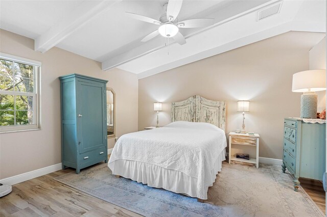 bedroom with ceiling fan, beamed ceiling, and light wood-type flooring