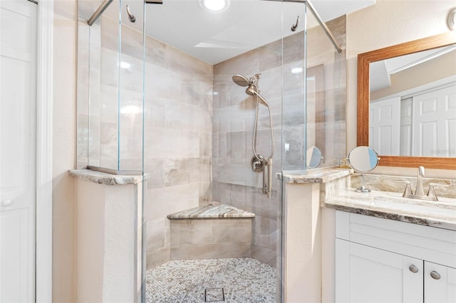 bathroom featuring a shower with door and vanity