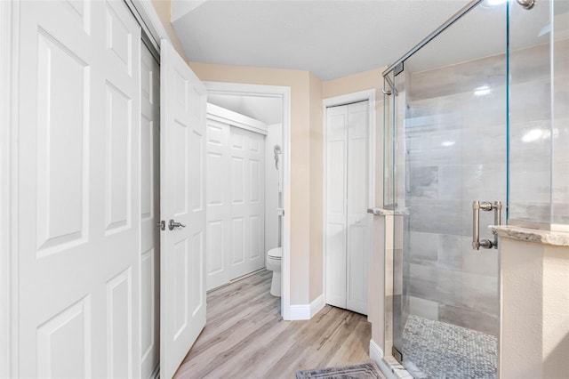 bathroom with wood-type flooring, toilet, and an enclosed shower