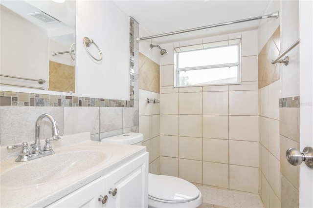 bathroom with vanity, tile walls, a tile shower, and tasteful backsplash