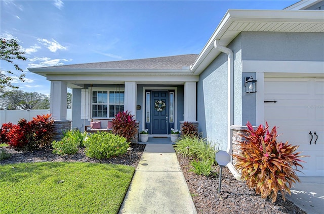 view of exterior entry with a garage and a porch