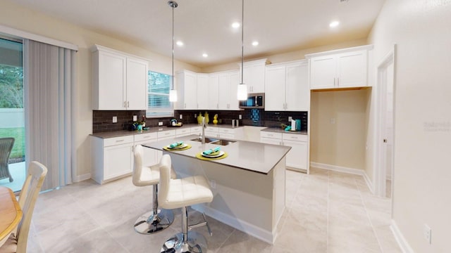 kitchen featuring pendant lighting, white cabinetry, light tile patterned floors, and a kitchen island with sink