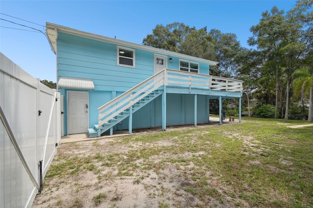 rear view of house with a wooden deck and a lawn