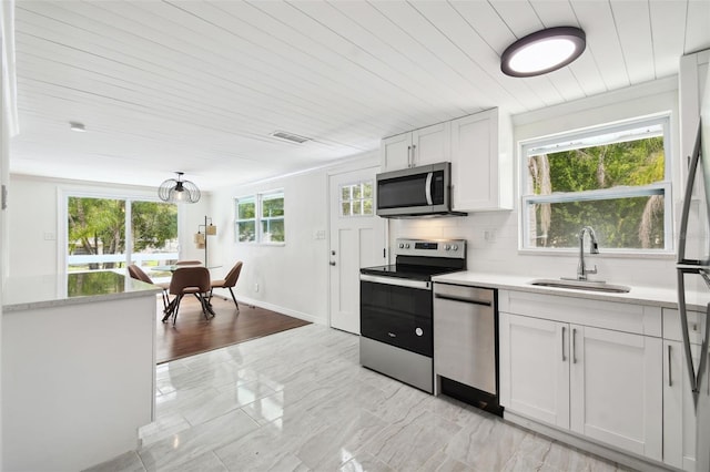 kitchen featuring a wealth of natural light, appliances with stainless steel finishes, white cabinetry, tasteful backsplash, and sink