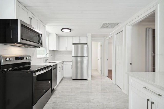 kitchen with appliances with stainless steel finishes, backsplash, white cabinetry, and sink