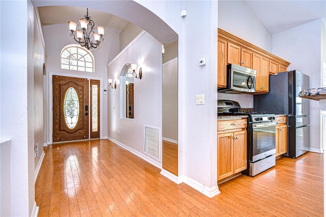 foyer with a notable chandelier, high vaulted ceiling, and light wood-type flooring